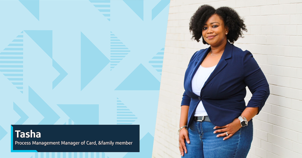 Tasha, Capital One Process Management Manager of Card, &family member, stands outside in front of a white brick wall